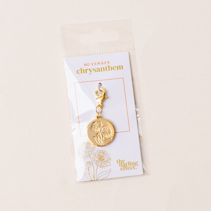 The-darling-effect November Jewelry Birth Flower Charm Gold features a chrysanthemum engraving and gold loop, mounted on a white NOVEMBER card. A meaningful gift, it's packaged in a clear sleeve.