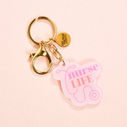 The-darling-effect’s Nurse Life Acrylic Keychain is a pink, durable accessory with a stethoscope design and gold clasp.