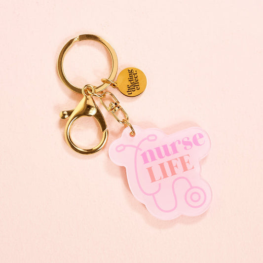 The-darling-effect’s Nurse Life Acrylic Keychain is a pink, durable accessory with a stethoscope design and gold clasp.