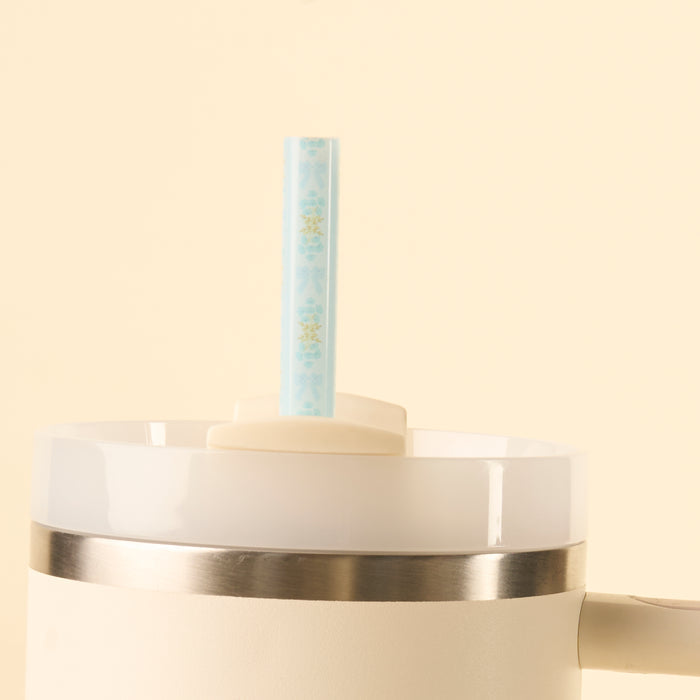 A close-up of the-darling-effect Oh So Fancy Blue 40 oz Tumbler Straw Set, a white tumbler with a silver rim and light blue reusable straw through the lid, set against a pale beige background.