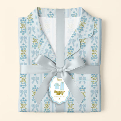 Folded Oh So Fancy Blue Slumber Party Pajama Pants Set by The Darling Effect, featuring a floral and bow design on ultra-soft fabric, tied with a satin ribbon and a “Slumber Party Pajama Party Kit” tag on a soft cream background.