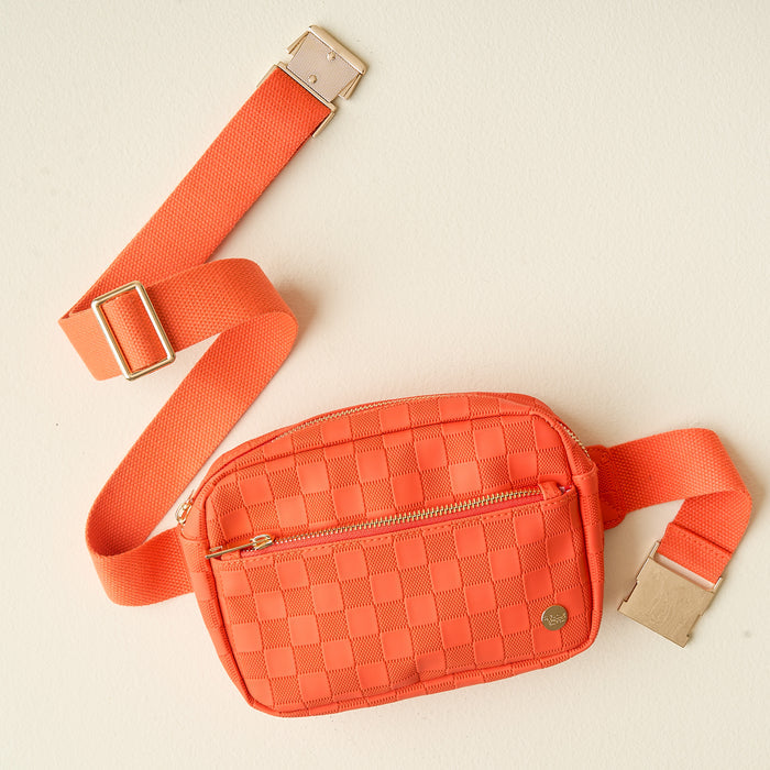 The Darling Effect’s Orange Urban Check Belt Bag features vegan leather, a woven design, matching adjustable strap, gold buckle, and front zip pocket—shown here against a light beige background.
