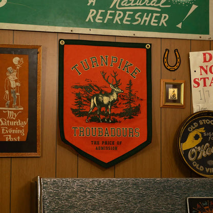 Forager Provisions LTD Oxford Pennant Turnpike Troubadours camp flag with a stag graphic on orange felt wall decor.