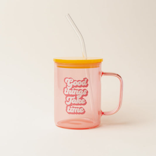 The Darling Effect’s Peach Good Things Take Time Color Glass Mug features a handle, yellow lid, and clear straw. Transparent pink glass displays “Good things take time” in bold white and pink letters on the front.