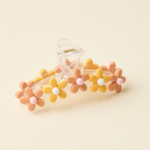The Darling Effect's Peachy Daisy Claw Clip is a clear plastic hair accessory featuring alternating yellow and peach daisy-shaped flowers with pastel centers, perfect for adding a stylish pop against any cream background.