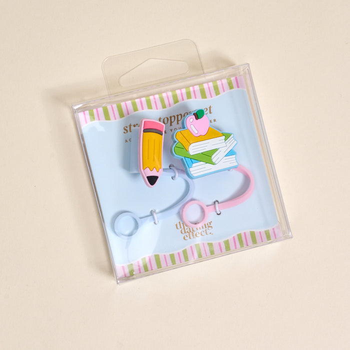 The Darling Effect’s Pencil Me In Straw Topper Set features two colorful plastic bookmarks—a pencil and a book stack with a pink flamingo—in clear, square packaging with pastel stripes, great for pairing with drinkware accessories or straw toppers.