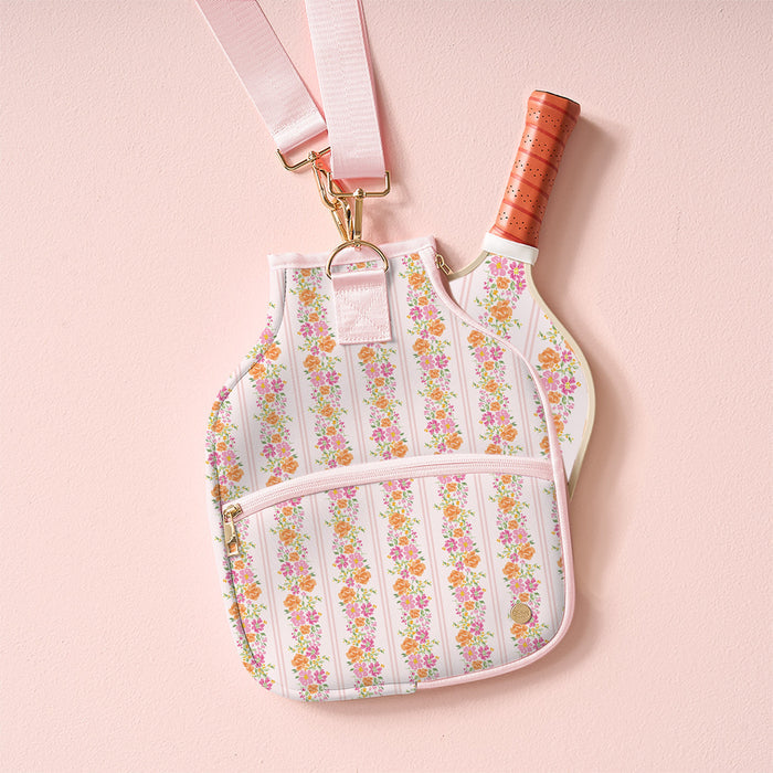 The-darling-effect’s Petal Parade Pink Pickleball Paddle Case features a pink and orange floral stripe pattern, pink crossbody strap, gold hardware, front zip pocket, and fits a paddle—combining style and function for pickleball players.