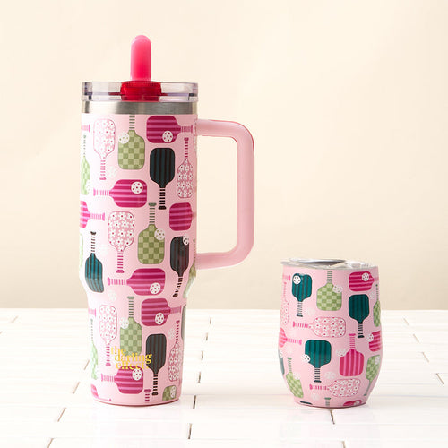 Two pink Pickleball Party 40 oz Lifestyle Flip Straw Tumblers by the-darling-effect, featuring colorful pickleball paddle designs and sturdy handles, rest on a white tiled surface with a light beige background.