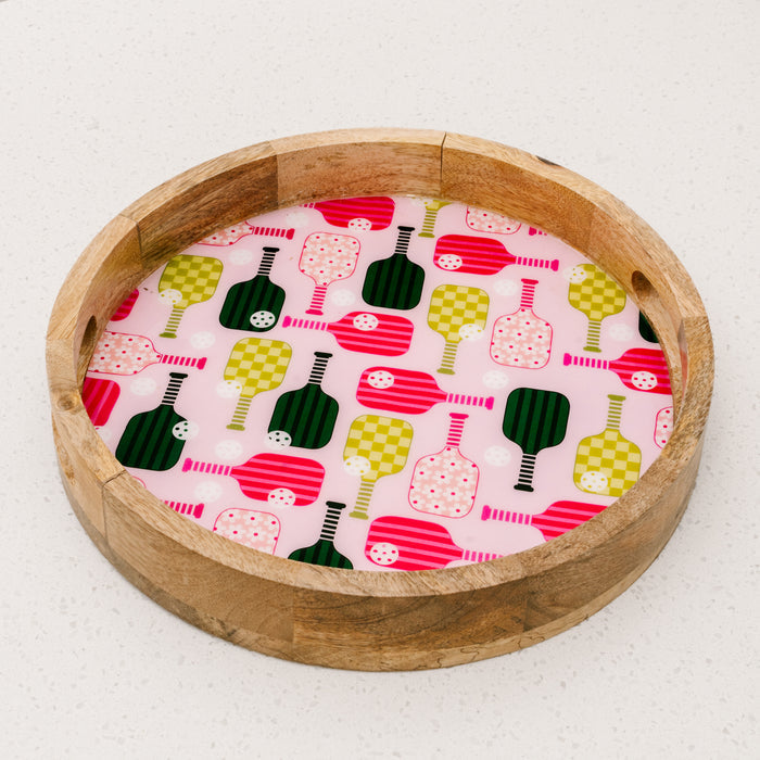 The Pickleball Party Large Round Wood Enamel Tray by the-darling-effect features a lively pink, green, and red paddle pattern on a crisp white base, adding vibrant style to your serving essentials.