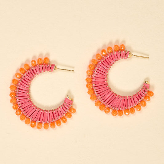 The Darling Effect’s Pink Sunset It-Girl Earrings feature pink hoops wrapped in raffia and orange faceted beads along the edge—lightweight, colorful, and perfect for adding boho flair to any everyday look.