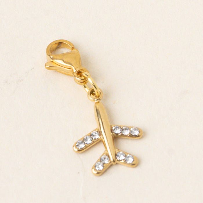 The Plane Jewelry Charm Gold by the-darling-effect features a gold airplane encrusted with clear gems and hangs from a lobster clasp—a standout charm bar piece for lovers of unique jewelry.