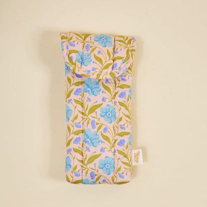 The Darling Effect's Poppin' Petals Aqua Puffy Sunglasses Case is a soft, machine-washable quilted case featuring blue flowers and green leaves on light beige, displayed against a plain background.