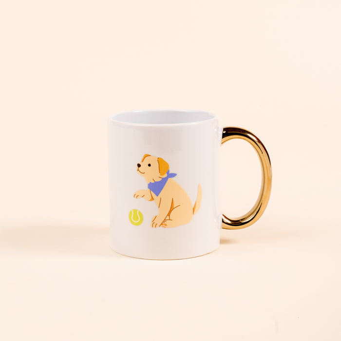 Sip your favorite drinks in The Darling Effect's Puppy Playtime 11 oz Cozy Cute Ceramic Mug, featuring a tan puppy in a blue bandana beside a green tennis ball on a white ceramic mug with a gold handle and light background.