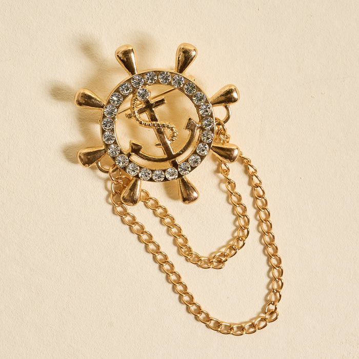 The Darling Effect's Sailor's Charm Timeless Brooch features a ship’s wheel with an anchor, sparkling rhinestone accents, and two gold chains—creating a vintage-inspired keepsake that's both elegant and unique.