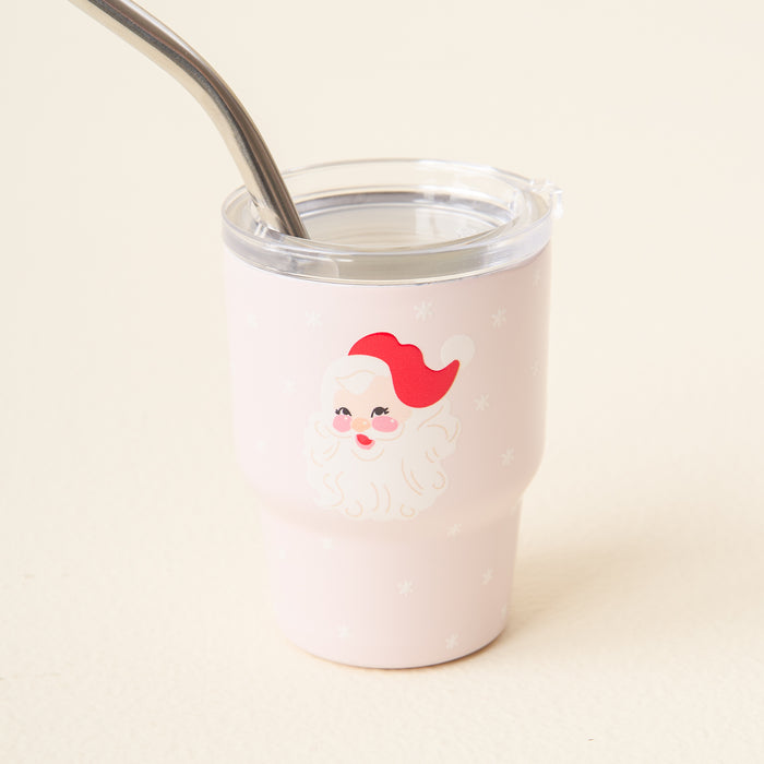 The Darling Effect Santa 2 oz Tiny Tumbler features a cute Santa face and snowflakes on a cream background, with a clear lid and metal straw—perfect for festive drinks on the go.
