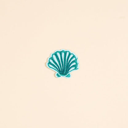 The Darling Effect’s Seashell Mix & Match Iron-On Patch features teal embroidered scallop shell details on a pale peach background—ideal for adding colorful flair to your jackets and accessories.