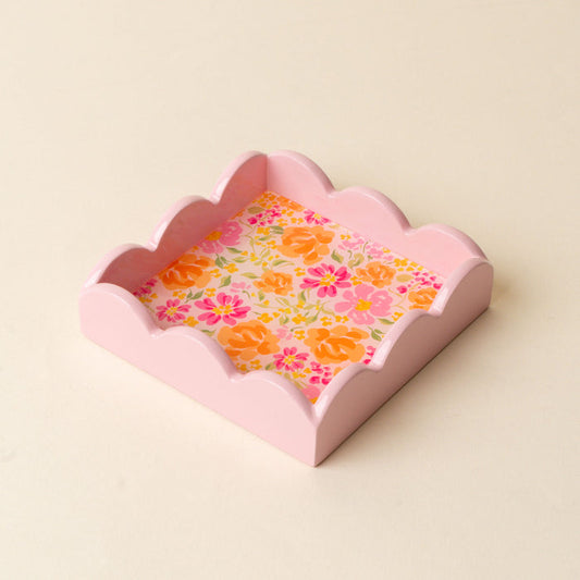 The Secret Garden Pink Scallop Trinket Tray by the-darling-effect is a pink, square tray with scalloped edges and a floral-patterned base featuring orange, yellow, and pink blooms on a light cream background—ideal for organizing jewelry or displaying accessories.