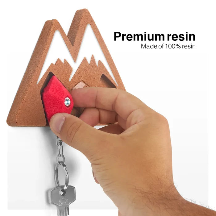 Hand placing keychain on Seven Peaks Keychain Rock Climber Holder, premium resin organizer for wall decor and keys.