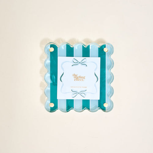 The Darling Effect's Sicily Stripes Teal Little Moments Acrylic Picture Frame features scalloped edges, alternating teal and light blue stripes, a centered card with gold text and bow illustration, plus gold studs in each corner for elegance.