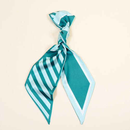 The Darling Effect's Sicily Stripes Teal Twirl & Tie Scarf Accessory features geometric stripes in teal and light blue, tied loosely and shown on an off-white background—ideal for versatile styling.