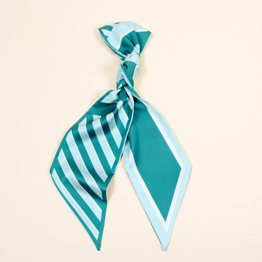 The Darling Effect's Sicily Stripes Teal Twirl & Tie Scarf Accessory features geometric stripes in teal and light blue, tied loosely and shown on an off-white background—ideal for versatile styling.