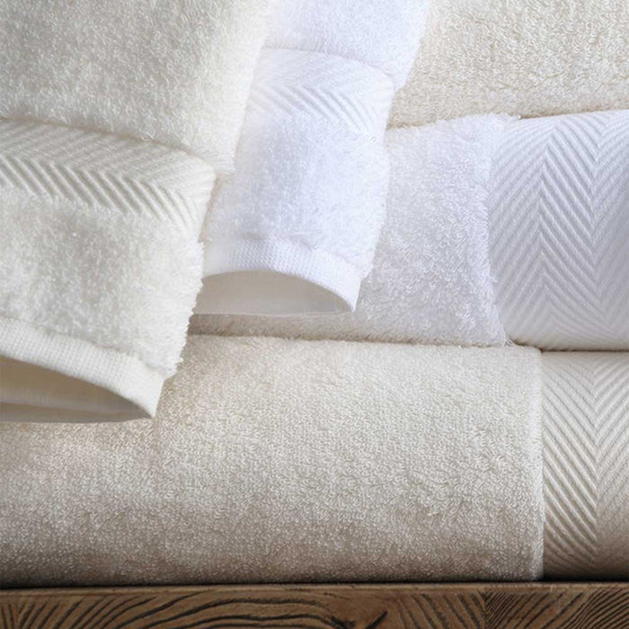 Stack of Signature Towels White and Ivory on a wooden surface