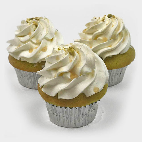 Three Simply Pistachio cupcakes topped with maple syrup and a sprinkle of pistachios