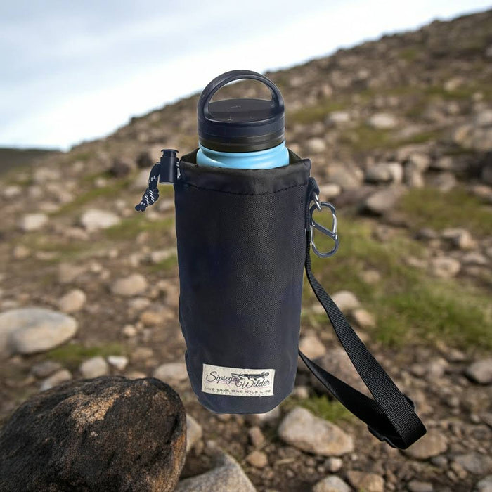 Sipsey Wilder Midnight Black 22oz Water Bottle Holder with waist strap, outdoor gear on rocky ground, hiking accessory.