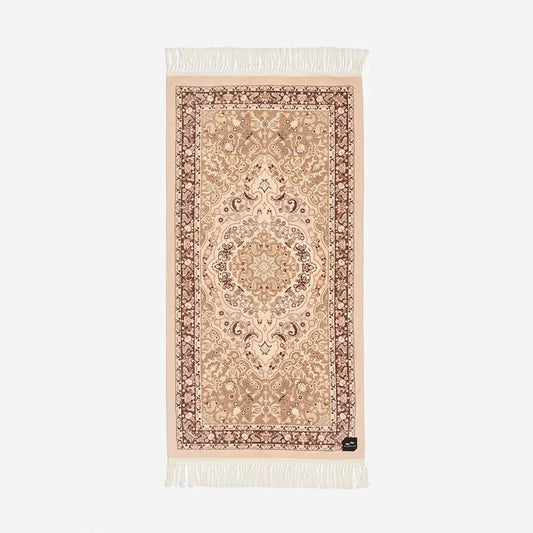 Slowtide Haven Beach Towel in Fawn features ornate central motif, floral border, and white fringe trim at both ends.