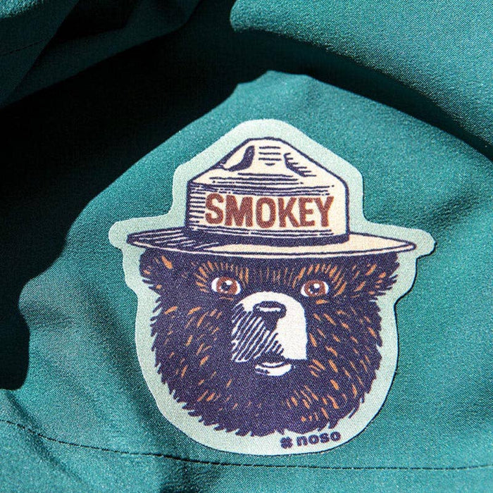 Forager Provisions LTD Smokey Bear retro logo NoSo repair patch applied to a dark green outdoor jacket fabric