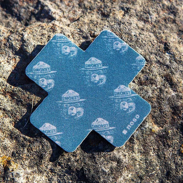Forager Provisions LTD Smokey Bear woodblock cross repair patch on a textured rock surface.