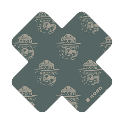 Forager Provisions LTD Smokey Bear woodblock cross repair patch in dark green with a repeating bear face pattern.