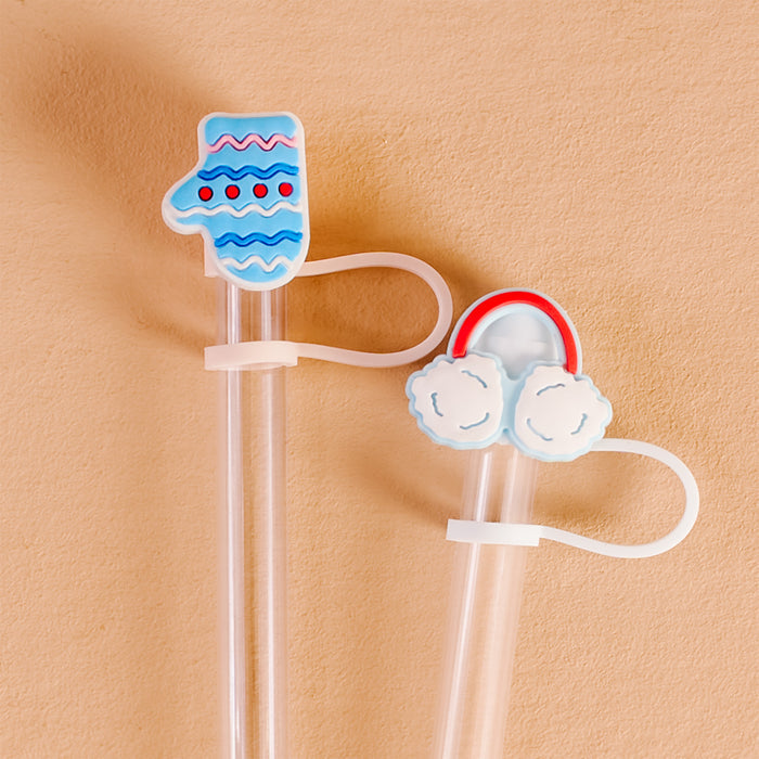 The Darling Effect's Snow Much Fun Straw Topper Set features two clear plastic straws with festive silicone toppers—a blue mitten and white earmuffs with a red band—perfect for adding fun to drinks, shown on a peach-colored background.