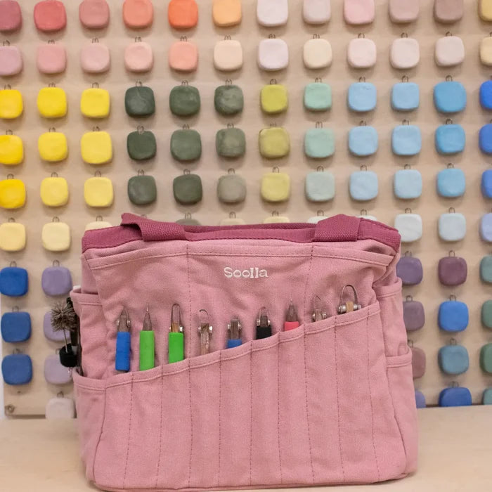Soolla Studio Pottery Artist Bag in Desert Rose Pink displayed in front of colorful square tiles. Pottery tote bag by Soolla.