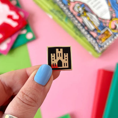 Blue-nailed hand holds Stacey McEvoy Caunt Medieval Abbey Pin with gothic castle enamel design, collectible lapel accessory.