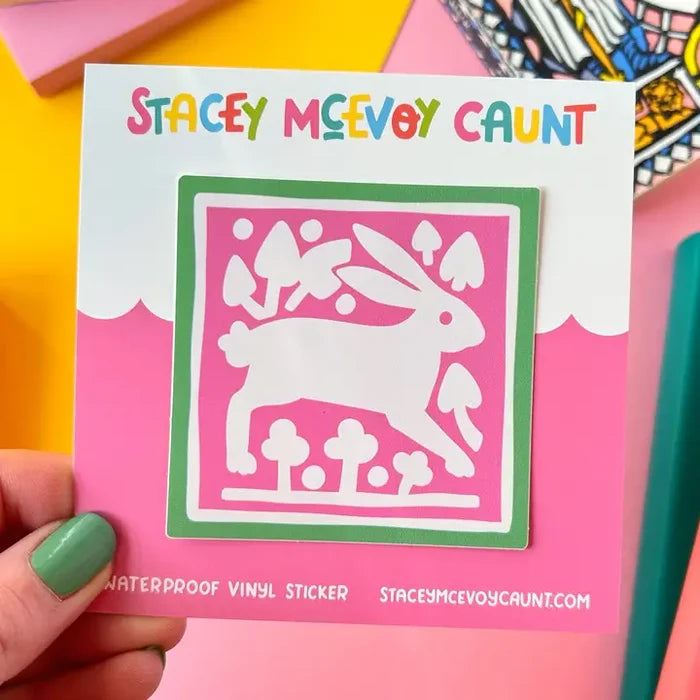 Hand holding Stacey McEvoy Caunt sticker: medieval white rabbit, trees, mushrooms. Unique tile design art for crafts, decor.