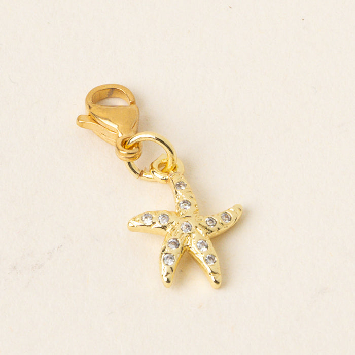 The Starfish Jewelry Charm Gold by the-darling-effect features a gold starfish shape with clear gemstones and a lobster clasp, offering one of jewelry’s most meaningful motifs from our charm bar collection.