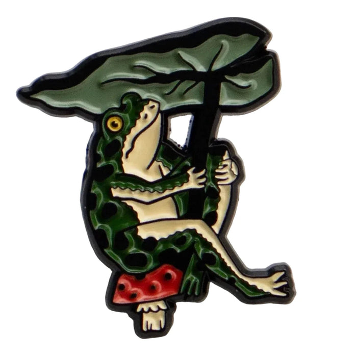 Forager Provisions LTD enamel pin featuring a green frog holding a large leaf umbrella while sitting on a mushroom.