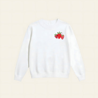 The Darling Effect’s Strawberry Patch Refined Knit Sweater is a classic white long-sleeve, featuring a small embroidered trio of red strawberries with green leaves on the left chest.