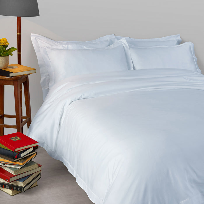 Suave-PaleBlue pillowcase and duvet cover on a bed with a lamp and books in the background