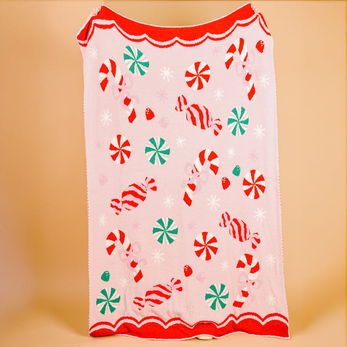 The Darling Effect's Sugar Rush Cozy Dreams Luxe Blanket features candy cane, peppermint, and wrapped candy patterns with a red scalloped edge—an ultra-soft, stylish blanket perfect for cozy snuggles.