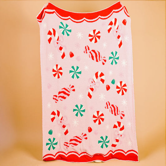 The Darling Effect's Sugar Rush Cozy Dreams Luxe Blanket features candy cane, peppermint, and wrapped candy patterns with a red scalloped edge—an ultra-soft, stylish blanket perfect for cozy snuggles.
