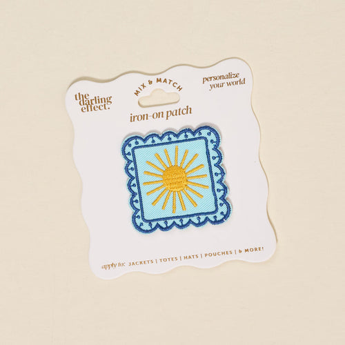 The Darling Effect's Sunshine Mix & Match Iron-On Patch features yellow rays on blue with a scalloped border, presented on a white card with gold text—perfect for customizing jackets or bags with a bright touch.