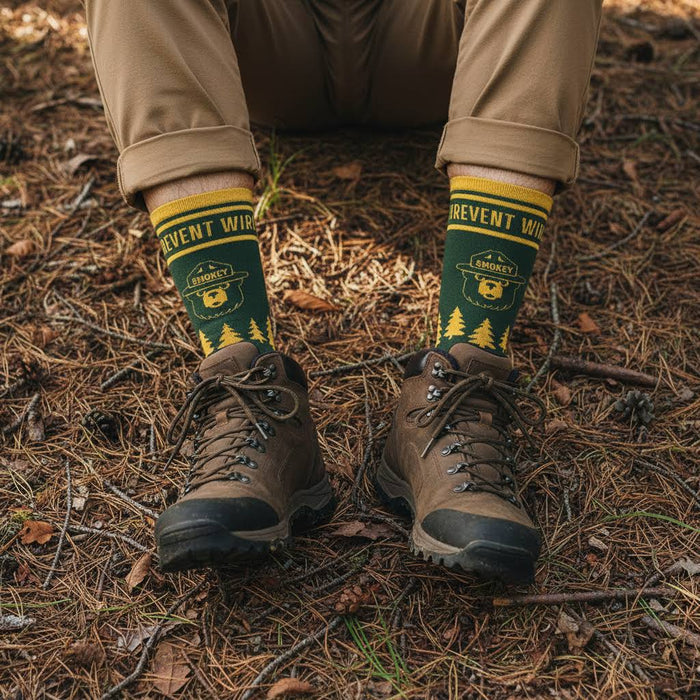 Wearing The Landmark Project Smokey Bear Emblem Sock - Pine, someone sits on a forest floor, outdoors adventure style.