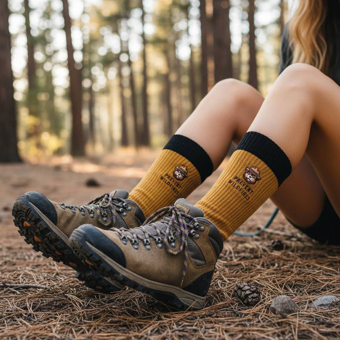 Forager Provisions LTD Smokey Bear message socks in mustard yellow worn with hiking boots in a forest setting