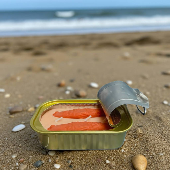 Tinned Fish Candle Oakmoss & Amber by Tinned Candle glows in sardine tin, beach sand background, unique gift idea.