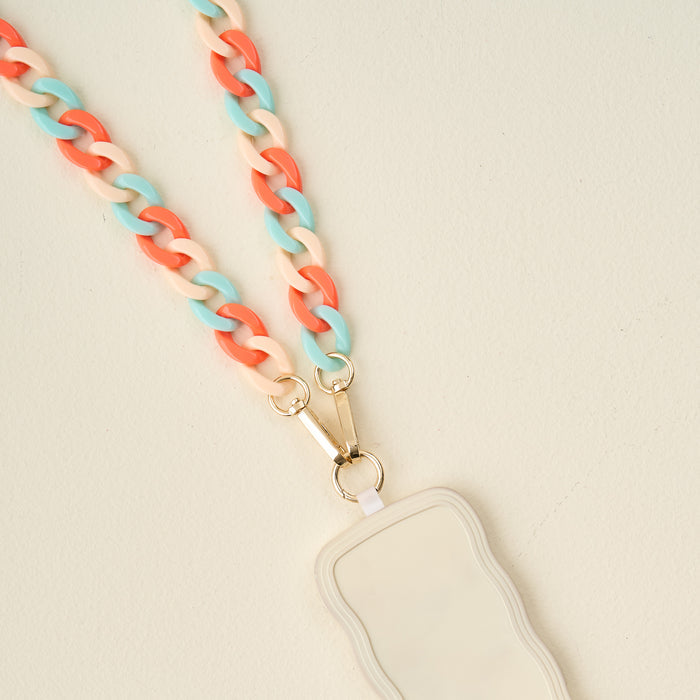 The Darling Effect Tri Coastal Hold the Phone Crossbody Chain features a chunky coral, cream, and teal design with gold hardware and a cream badge holder—combining fashion and function as both a lanyard and crossbody phone chain.