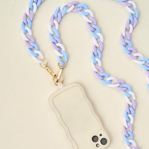 The Darling Effect’s Tri Cool Hold the Phone Crossbody Chain in blue, purple, and white pairs with a cream phone case with wavy edges for a trendy, hands-free way to carry your device anywhere.