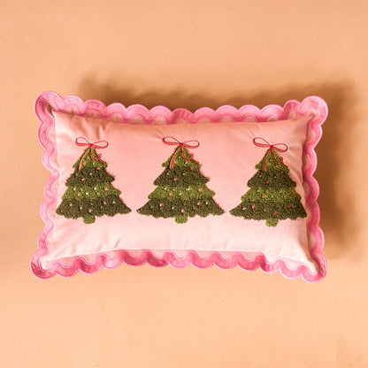 The Darling Effect’s Twinkling Trees Scalloped Rectangle Throw Pillow features three embroidered green Christmas trees with red bows on a pink background, adding festive flair to your space—perfect for holiday pillow collections.