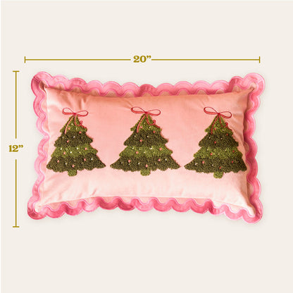 The Darling Effect's Twinkling Trees Scalloped Rectangle Throw Pillow adds a cozy, festive touch with pink fabric, embroidered green Christmas trees, red bows, and pink ornaments. Measures 12" x 20".